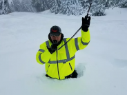 Rescuer waist deep in snow using radio