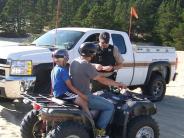 People on dune buggy next to patrol officer and vehicle